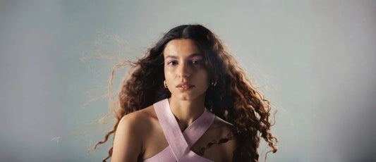 A woman demonstrating the plopping technique for enhancing natural curls in her hair.