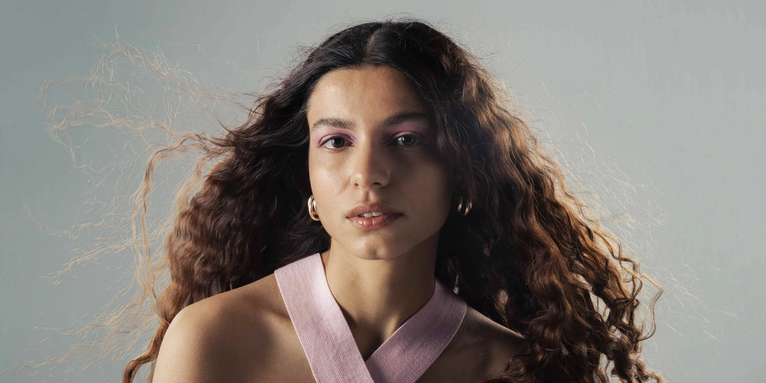 A woman with low fade curly hair style showing off her beautiful texture and sharp fade line. 
